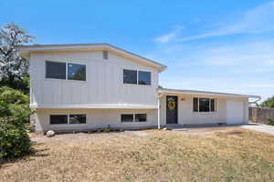 Tri-level home with brick siding, board and batten siding, an attached garage, and concrete driveway
