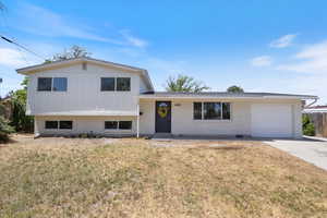 Tri-level home featuring a garage, brick siding, concrete driveway, and board and batten siding