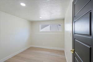 Unfurnished room with light wood-style flooring, a textured ceiling, and recessed lighting