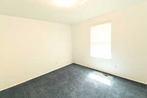 Unfurnished room with dark colored carpet and baseboards