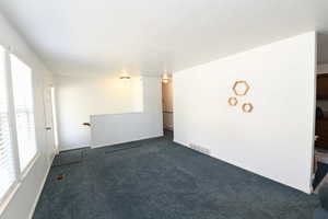Unfurnished room featuring dark carpet and a textured ceiling