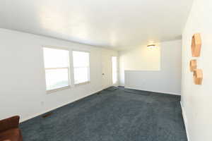 Spare room with dark colored carpet and baseboards