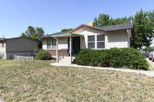 Single story home with a chimney and a front yard
