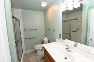 Full bath featuring vanity, a shower stall, and a textured ceiling