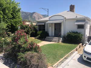 View of front of house featuring a mountain view, a front lawn, and a chimney