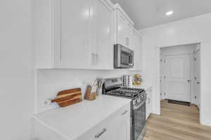 Kitchen featuring stainless steel appliances, white cabinets, decorative backsplash, and recessed lighting