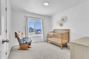 Carpeted bedroom featuring baseboards and a nursery area