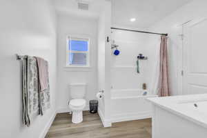 Full bathroom featuring shower / bath combination with curtain, wood finished floors, and vanity