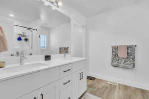 Full bath featuring double vanity, wood finished floors, and a shower