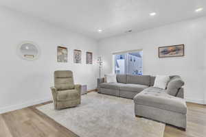 Living area with light wood-style flooring and recessed lighting