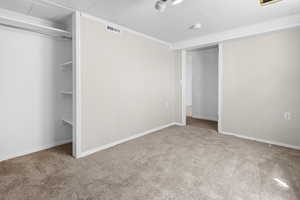 Unfurnished bedroom with crown molding, carpet, and a closet