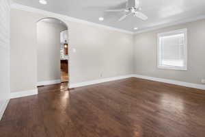 Spare room featuring arched walkways, ceiling fan, dark wood-style flooring, ornamental molding, and recessed lighting