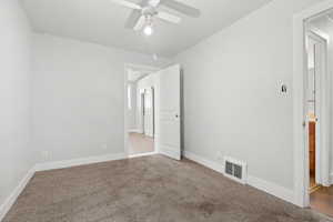 Carpeted empty room with ceiling fan and baseboards