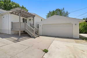 View of front of property with a detached garage, an outdoor structure, and a pergola