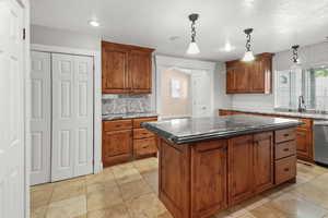 Kitchen with backsplash, decorative light fixtures, dishwasher, and a center island
