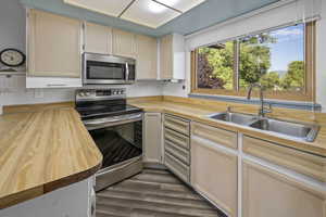 Kitchen with appliances with stainless steel finishes, wooden counters, and dark wood finished floors