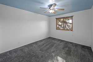 Unfurnished room with dark colored carpet and ceiling fan