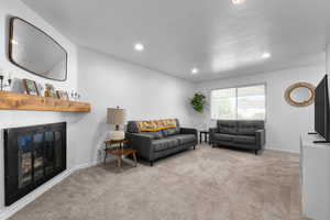 Living area featuring carpet flooring, recessed lighting, and a glass covered fireplace