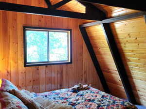 Bedroom with wood walls and vaulted ceiling