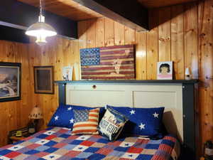 Bedroom with wooden walls and beamed ceiling