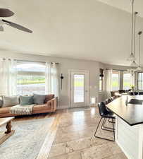 Living area with ceiling fan, a chandelier, and light stone finish flooring