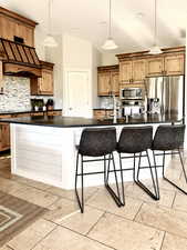 Kitchen with stainless steel appliances, range hood, dark countertops, backsplash, and recessed lighting