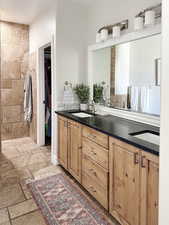 Bathroom with double vanity, stone tile flooring, and a spacious closet