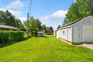 View of grassy yard with an garage and playhouse