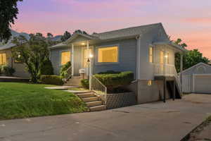 View of front of property with a driveway, yard, garage, and porch