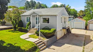 View of front of property with a driveway, yard, garage, and porch
