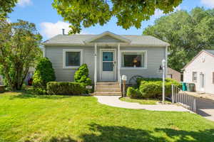 View of front of home with a front lawn and roof with shingles