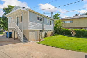 View of side of property featuring a yard, stairway, and concrete driveway