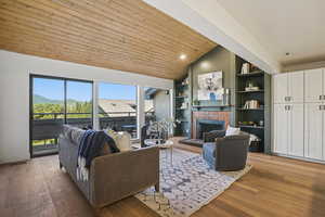 Living room featuring a fireplace, wood finished floors, high vaulted ceiling, and built in shelves