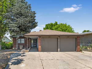 View of front of house with brick siding, driveway, an attached garage, and a shingled roof