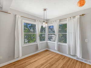 Unfurnished dining area with wood finished floors and baseboards
