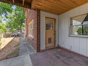 Doorway to property with brick siding and a patio area