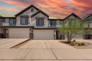 View of front facade featuring stucco siding, stone siding, an attached garage, and concrete driveway