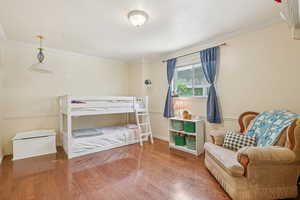 Bedroom featuring ornamental molding and wood finished floors