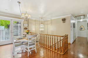 Dining room featuring a chandelier, wood-type flooring, crown molding, and attic access