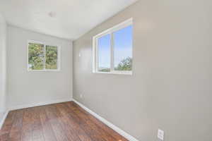 Unfurnished room with baseboards and dark wood-style flooring