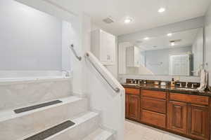 Bathroom featuring double vanity, tile patterned flooring, a bath, and recessed lighting