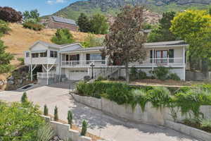 View of front facade with stairs, a garage, covered porch, driveway, and a mountain view
