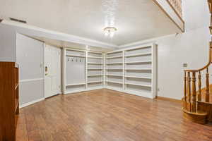 Unfurnished room with a textured ceiling, ornamental molding, hardwood / wood-style floors, and stairway