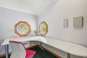 Office area featuring carpet, built in desk, and vaulted ceiling