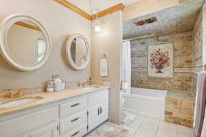 Full bathroom with tile patterned floors, double vanity, shower / bath combination with curtain, and crown molding