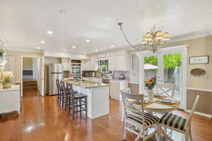 Dining room with a chandelier, ornamental molding, wood finished floors, and recessed lighting