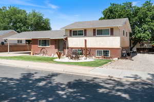 View of front of property with brick siding, stucco siding, driveway, and a carport