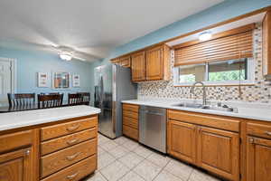 Kitchen featuring appliances with stainless steel finishes, brown cabinets, backsplash, and a textured ceiling