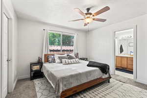 Bedroom with light colored carpet, ensuite bathroom, and a ceiling fan