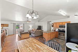 Dining room featuring vaulted ceiling, a chandelier, wood finished floors, and a ceiling fan